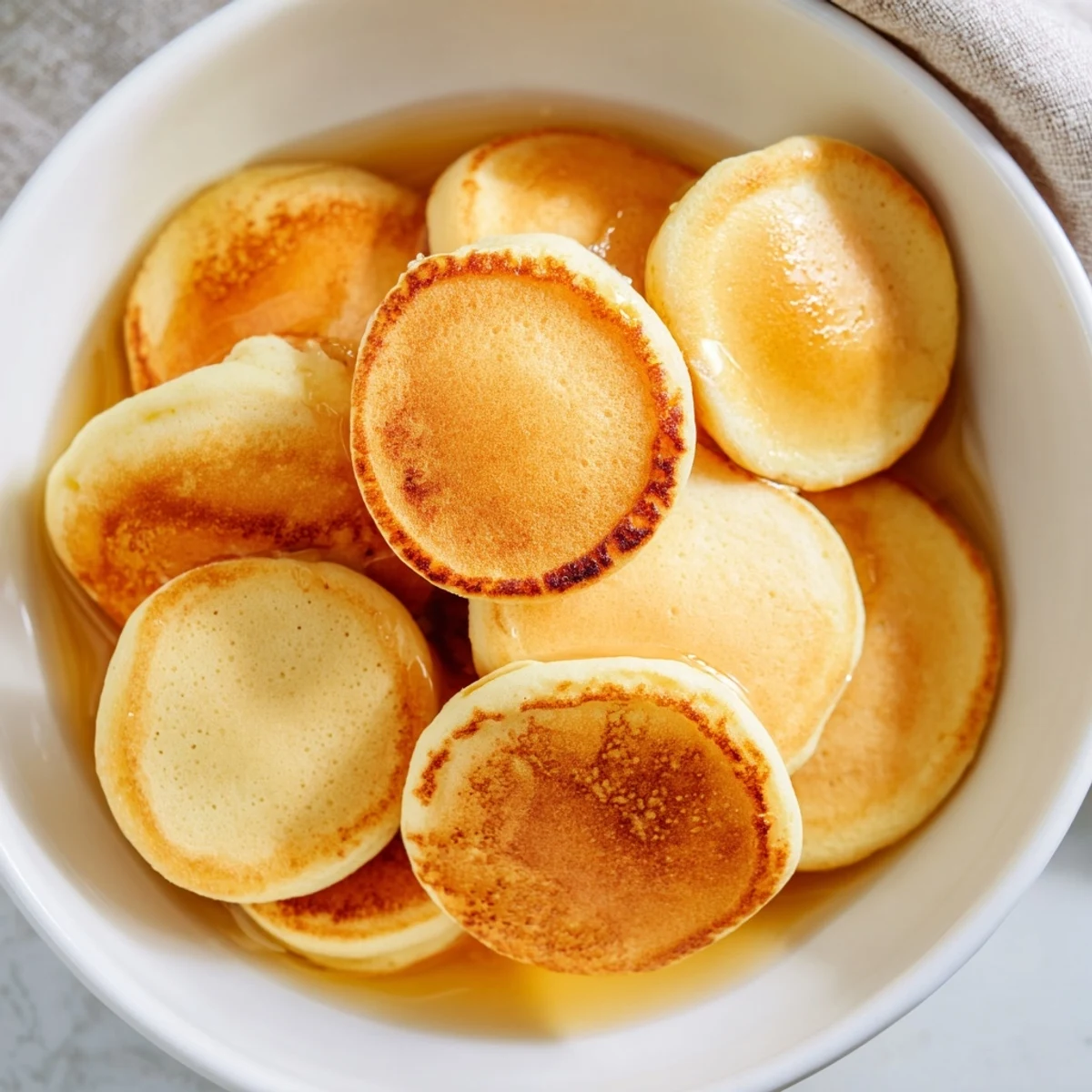 Warm, sweet fluffy pancake cereal swimming in milk, ready to eat for a delicious meal.