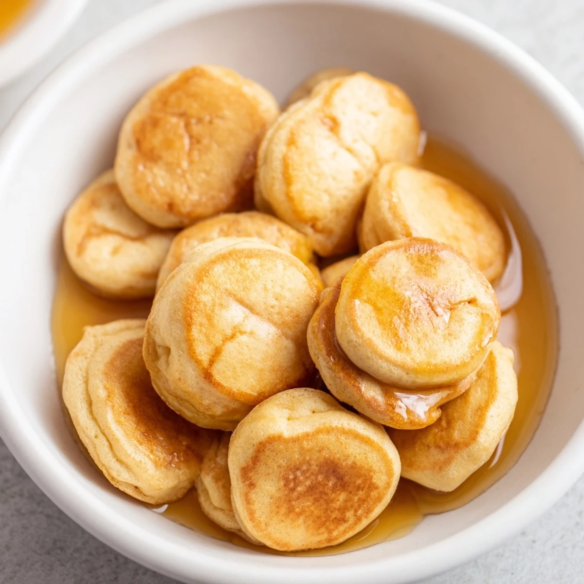 Fluffy pancake cereal, tiny golden pancakes piled in a bowl, perfect for a breakfast treat.