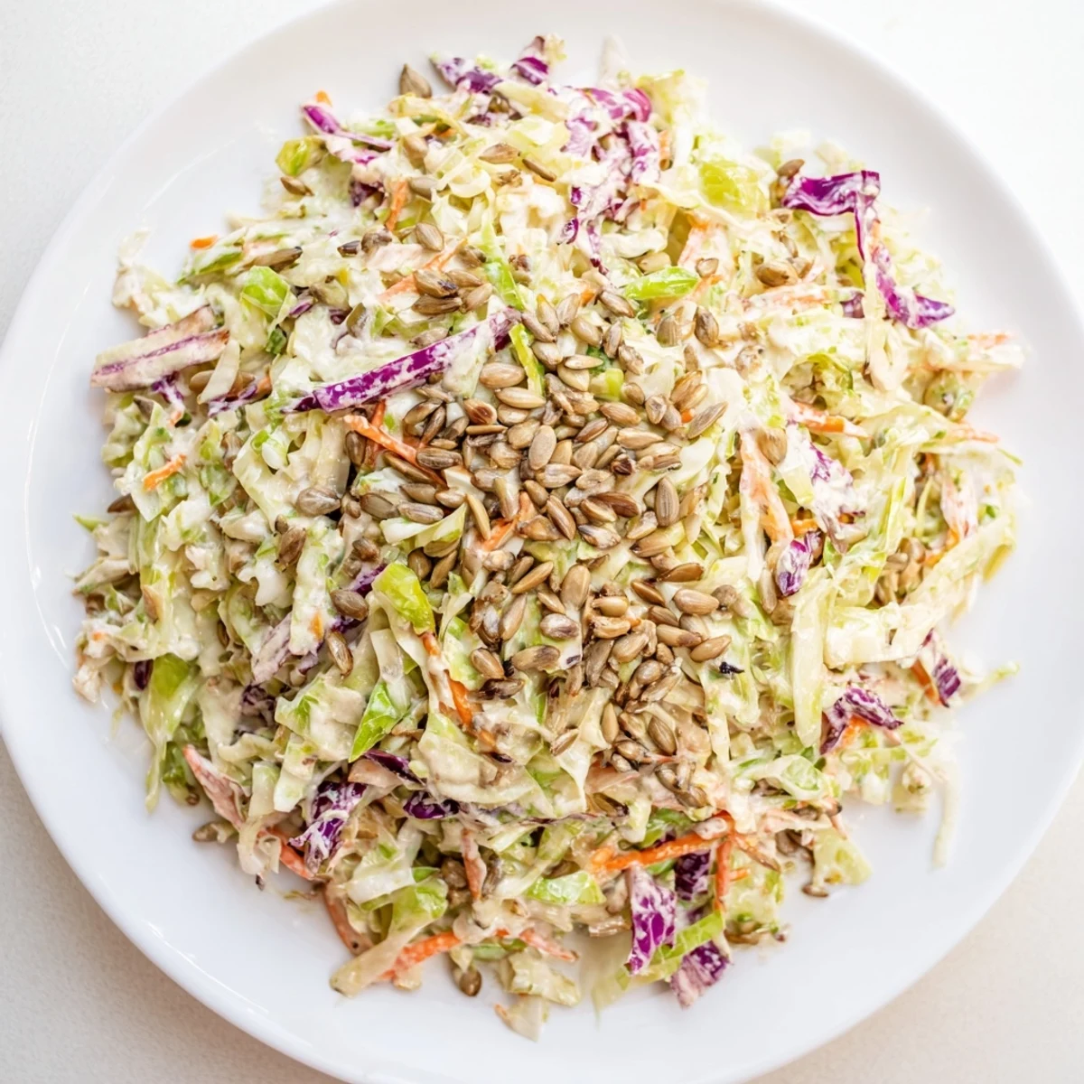 Creamy crunchy coleslaw salad, vibrant with shredded cabbage, carrots, and sunflower seeds for a picnic.