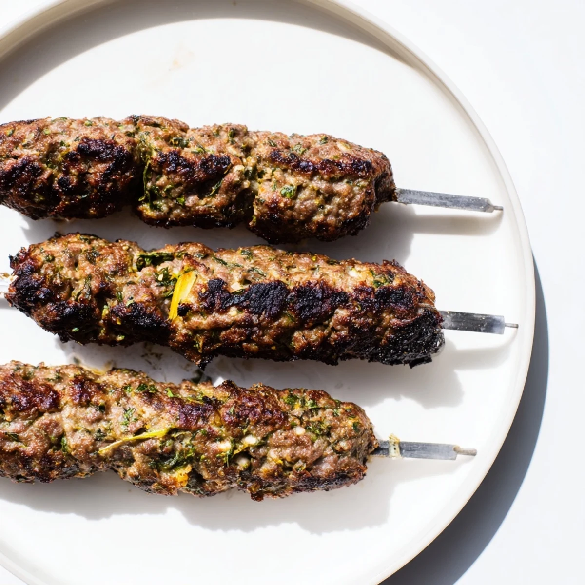 Smoky, grilled Iraqi Kebab Tikka skewers, browned with slightly charred edges, ready to serve with fresh herbs.