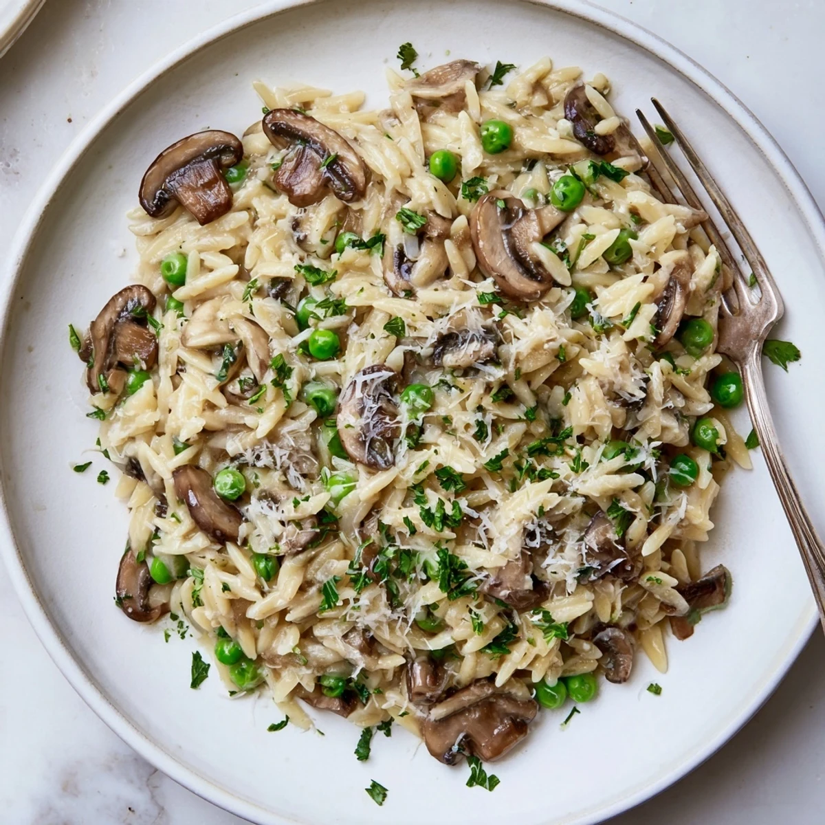 Golden Orzo Mushroom Risotto-Style steaming in a skillet, featuring sautéed cremini mushrooms and tender green peas.