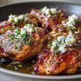 Sizzling Greek Chicken with Lemon and Feta topped with crumbled feta and lemon wedges.