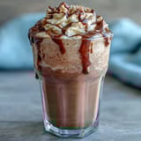 Creamy vanilla bean frappuccino protein shake with frosty ice and vanilla bean specks, perfect for a refreshing breakfast or post-workout treat.