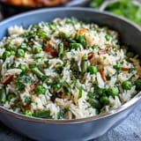 2. Aromatic rice pilaf featuring tender spring peas, chopped mint, and parsley, offering a refreshing and colorful vegetarian side dish.  