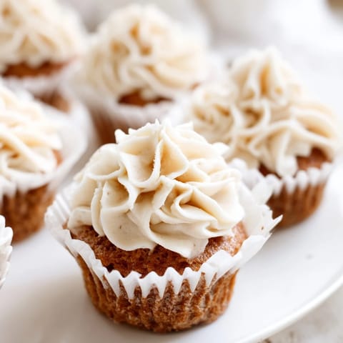 Close-up of baked vanilla cupcakes topped with sweet, creamy homemade buttercream frosting.