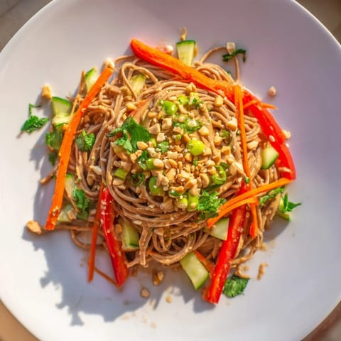 This image shows a beautifully arranged Spicy Peanut Noodle Salad, drizzled with creamy sauce.