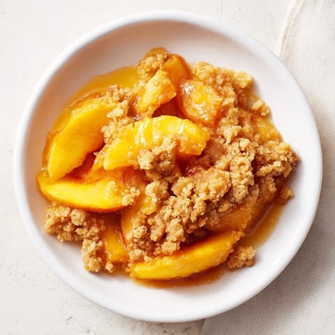Freshly baked Peach and Ginger Crumble, served warm, with a buttery, crispy topping and juicy peaches.