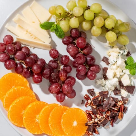 Elegant Grapes of Fortune dessert board features twelve grapes, diverse treats, and cheeses for New Year's.