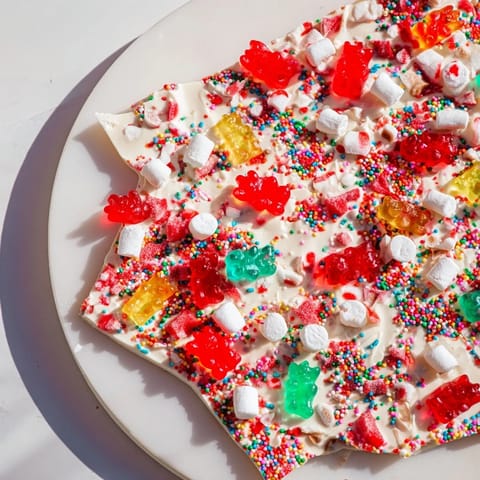 A festive tray of white chocolate bark studded with colorful gummy bears and crushed candy canes.