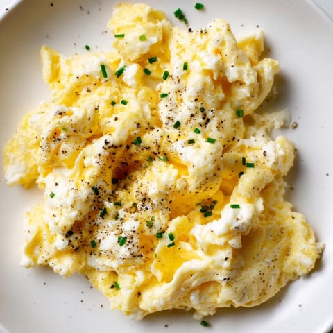 Golden Cottage Cheese Scrambled Eggs, seasoned perfectly, with fresh herbs on top for brunch.