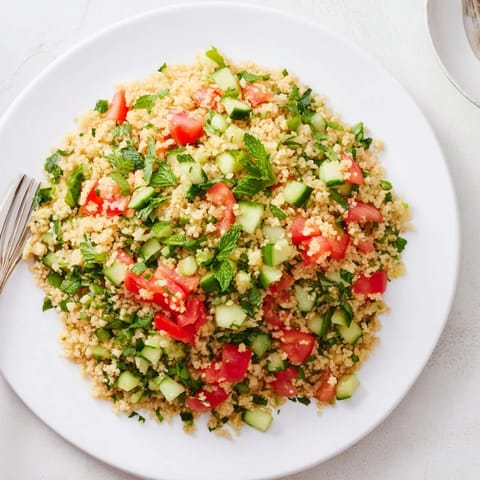 A chilled bowl of fluffy Bulgur Wheat Salad Tabbouleh topped with fresh mint and scallions, served ready to eat.