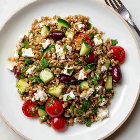 A refreshing bowl of Farro Salad Mediterranean with crisp cucumbers, red onion, and fresh herbs, served as a perfect vegetarian side or light lunch.