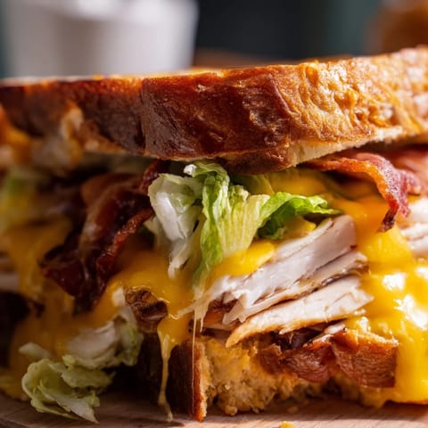A close-up of the Turkey Club Grilled Cheese, revealing layers of roasted turkey, fresh lettuce, and tomato.  