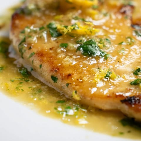 Golden-brown Spinach Lemon Butter Chicken is plated beside wilted greens, garnished with fresh parsley and lemon slices.  
