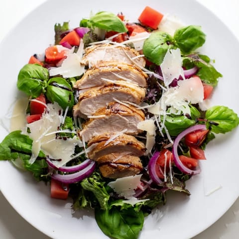 Sliced grilled chicken with a vibrant tomato-basil bruschetta topping, served over fresh mixed greens and shaved Parmesan for a light, zesty main dish.
