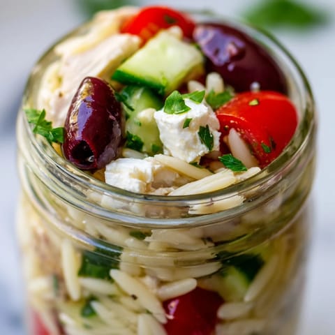 A top-down view showcases fresh Mediterranean ingredients in meal prep jars, perfect for healthy grab-and-go lunches.