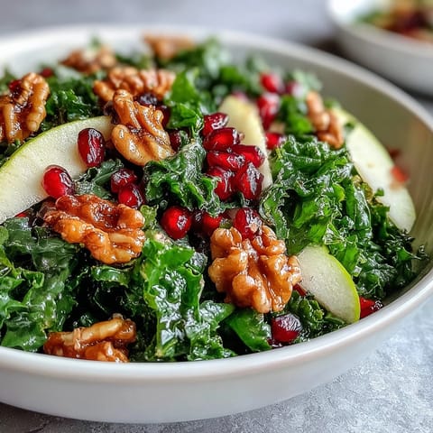 Kale and Pomegranate Bowl topped with crunchy walnuts and sliced apples on a rustic plate. 