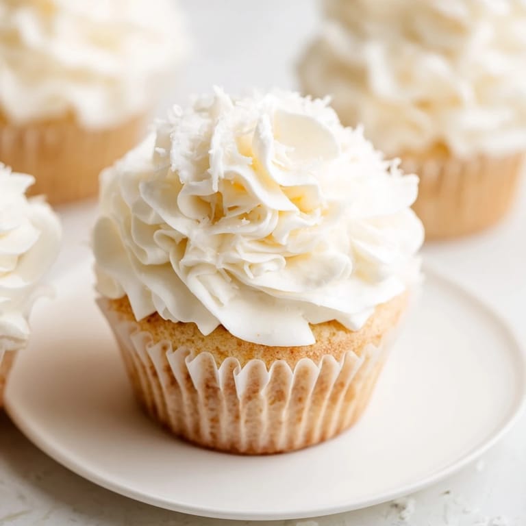 Freshly frosted vanilla cupcakes, ready to eat, featuring a perfect dollop of buttercream.