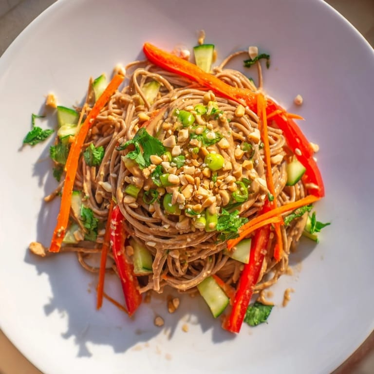 This image shows a beautifully arranged Spicy Peanut Noodle Salad, drizzled with creamy sauce.
