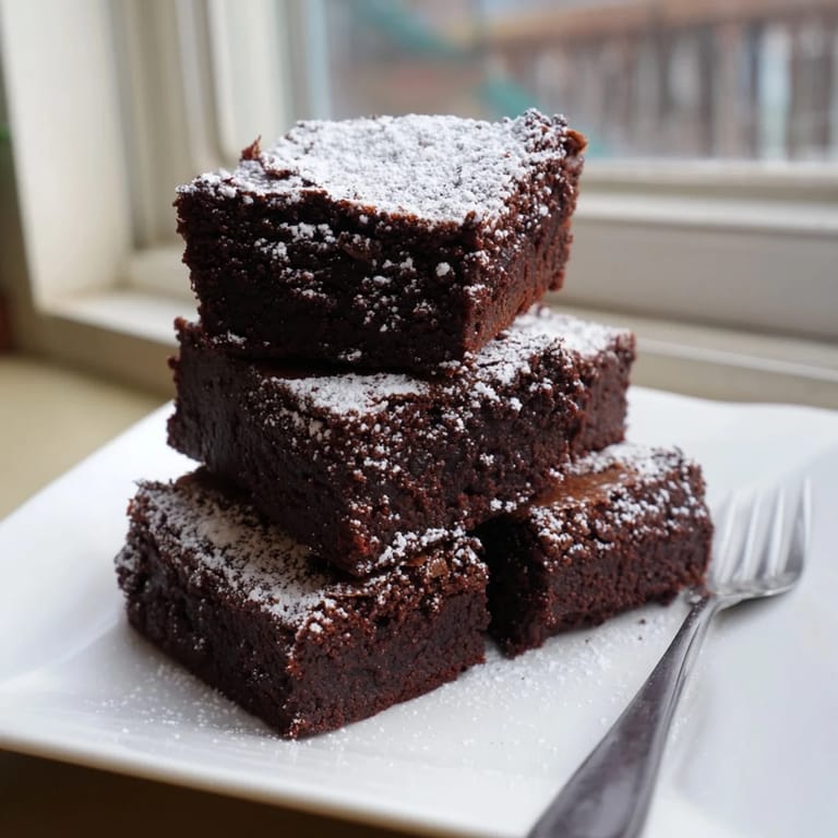 Freshly baked brownie squares, a rich American dessert, invitingly dusted with sweet powdered sugar.