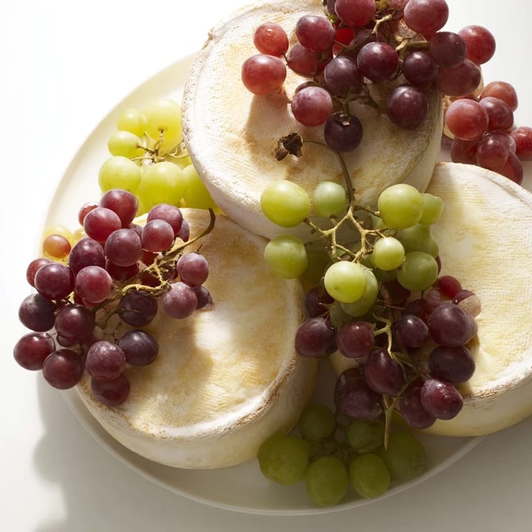 A visually stunning Rustic Vineyard platter, featuring young cheese wheels and vibrant grapevine accents.