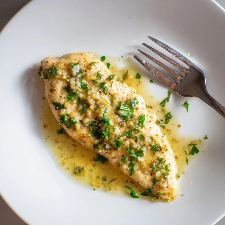 Tender Lemon Pepper Chicken in a skillet, garnished with fresh parsley and bright lemon zest for a savory meal.