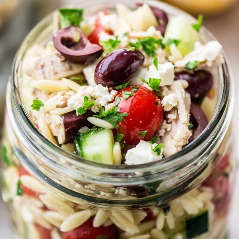 Bright, appetizing Greek pasta chicken salad jars with olives and cucumbers, served ready for a refreshing lunch.