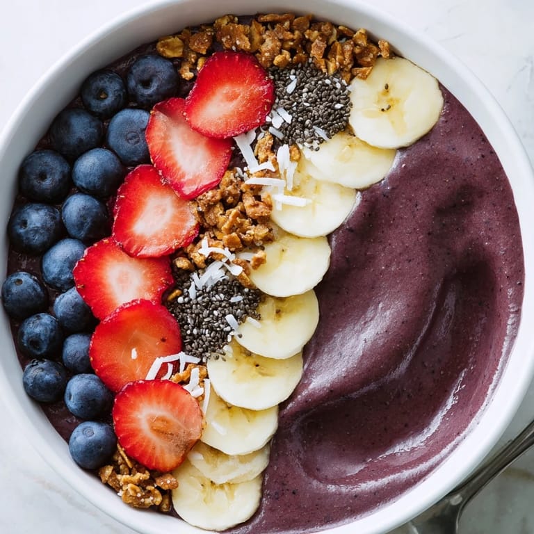 Colorful vegan acai berry smoothie bowl with mixed berries, pumpkin seeds, and gluten-free granola in a white bowl.