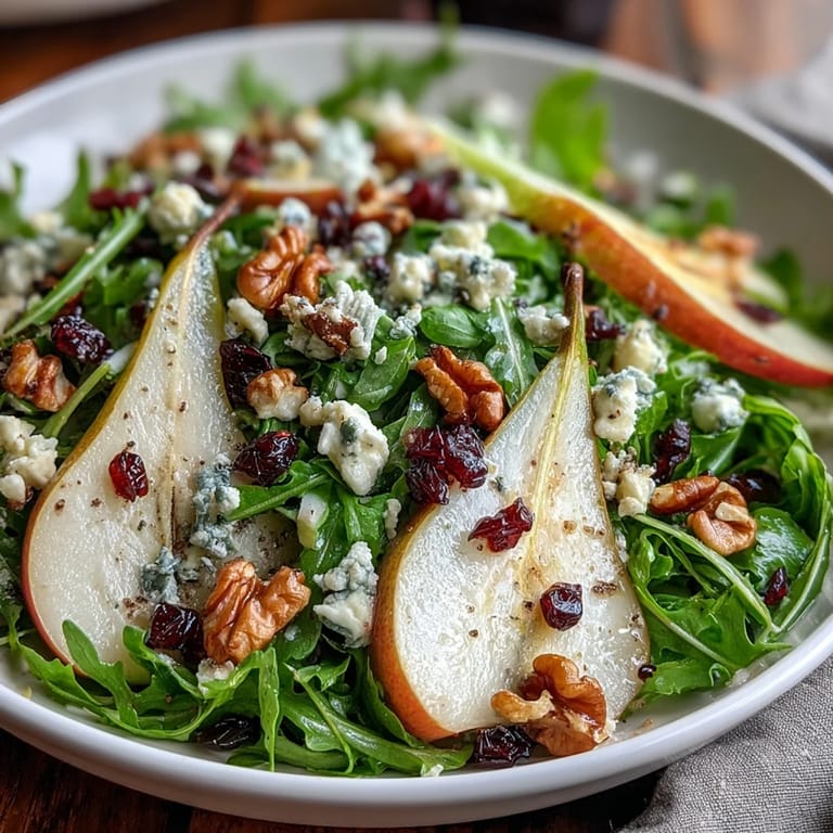 A plated Arugula and Pear Bowl drizzled with balsamic dressing, garnished with chopped nuts, served as a light vegetarian lunch.