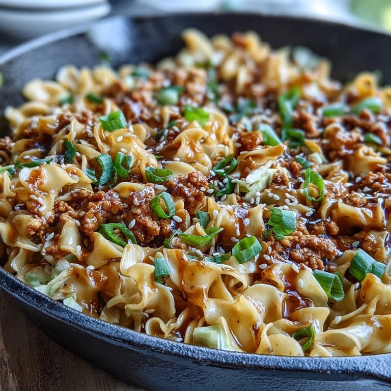 A hearty bowl of Creamy Potsticker Noodle Stir-Fry topped with scallions and sesame seeds, ideal for easy weeknight dinners.