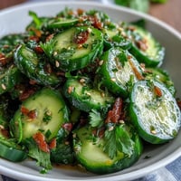 Crisp Asian cucumber salad with sesame and rice vinegar dressing, garnished with toasted sesame seeds and green onions. Refreshing, tangy, and perfect for summer meals.