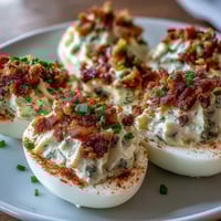 Bacon Ranch Deviled Eggs with crispy bacon and creamy ranch filling, garnished with fresh chives and paprika for a flavorful appetizer.