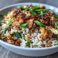 Aromatic fried rice with scrambled eggs and chili crisp, garnished with fresh scallions and sesame seeds for extra flavor.